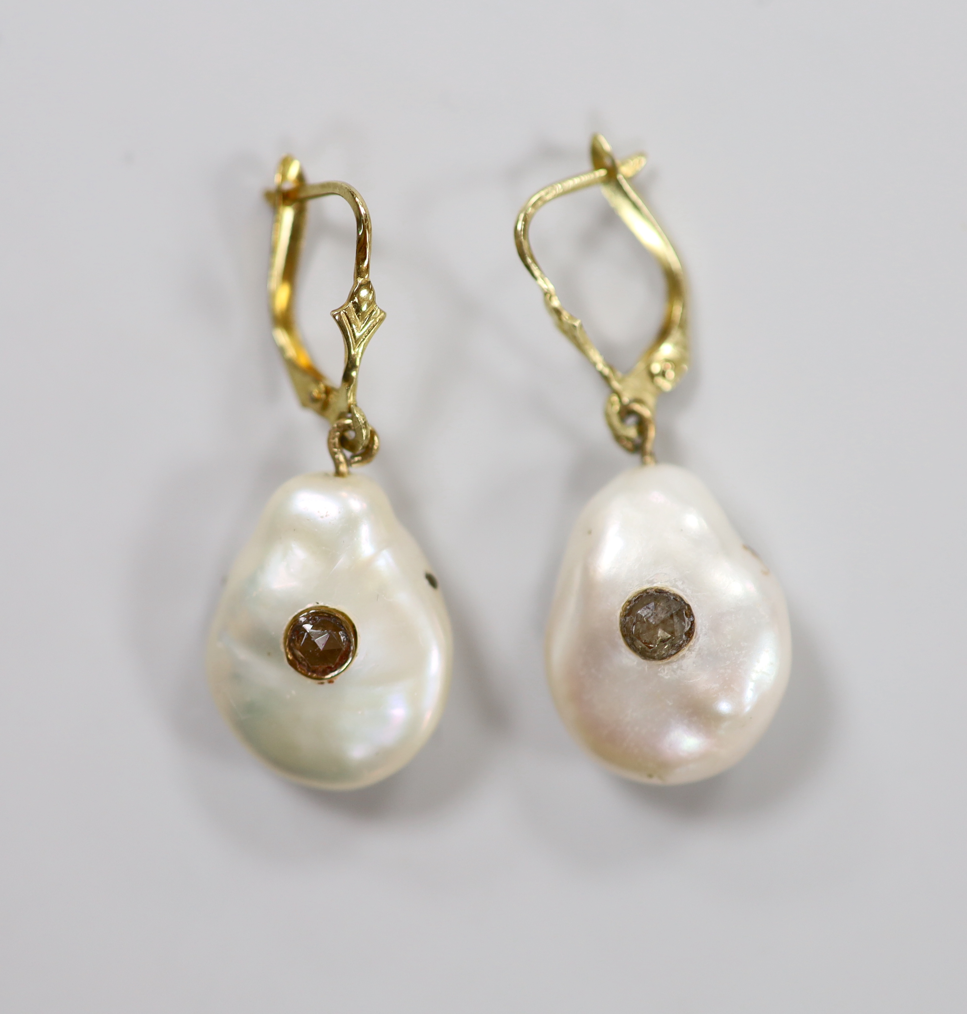 A pair of yellow metal and baroque pearl set drop earrings, each with inset rose cut diamond, pearl 17mm, gross weight 6.4 grams.